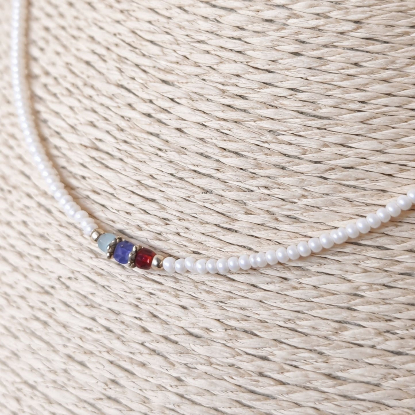 Collar de perlas blancas con detalles en azul y rojo, estilo elegante y moderno, ideal para ocasiones especiales.