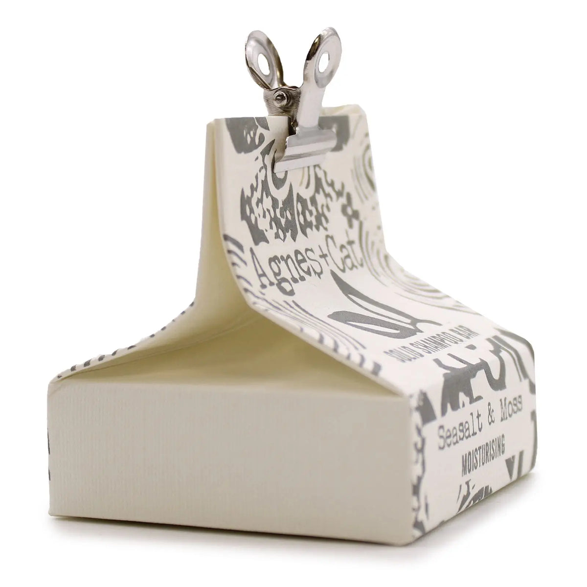 Champú sólido Agnes+Cat de sal marina y musgo en caja de papel blanco con diseño gris y pinza metálica. Fondo blanco.