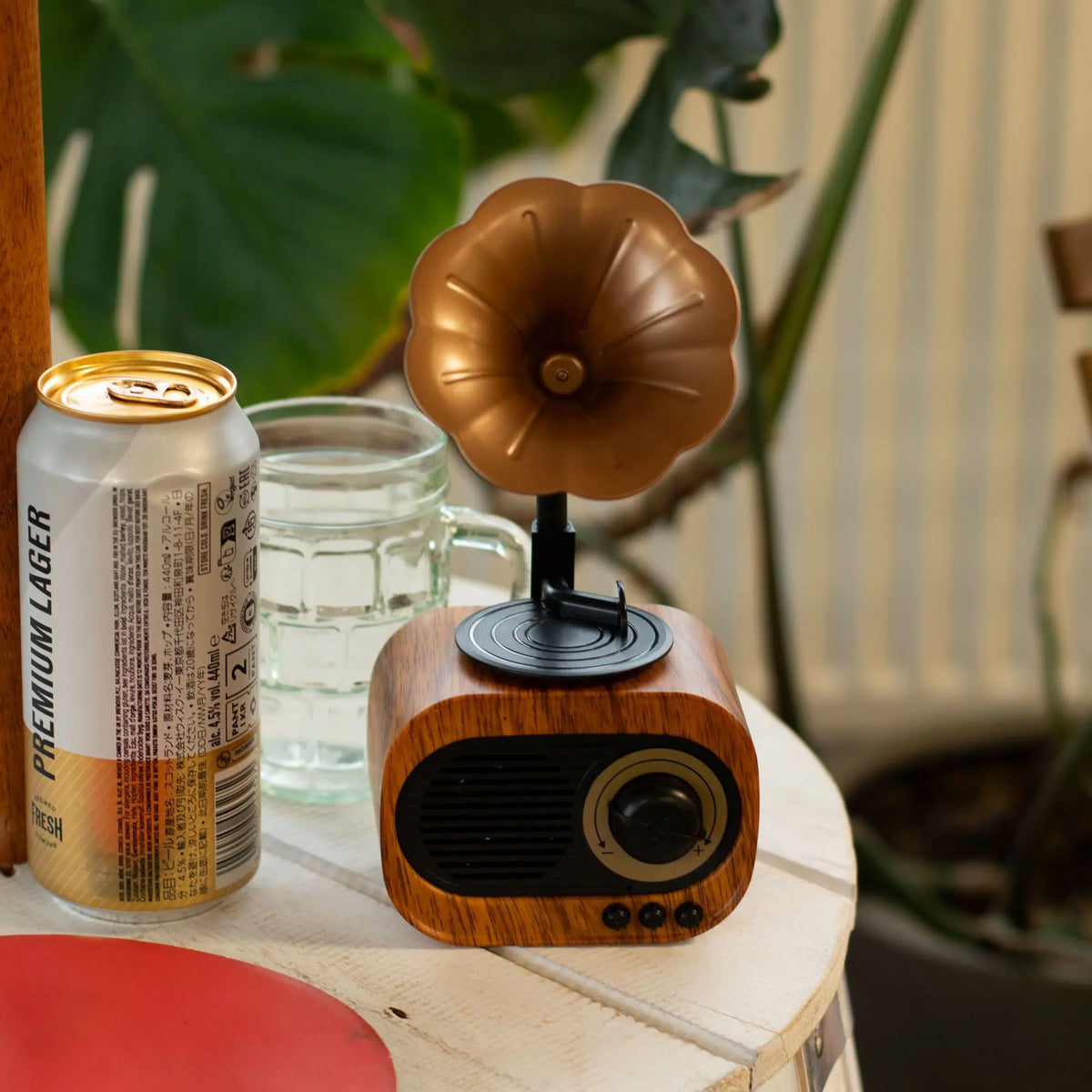 Altavoz Bluetooth estilo gramófono retro con base de madera, bocina color bronce y control frontal sobre mesa clara.