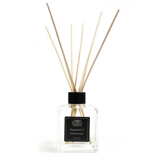 Difusor de vidrio transparente cuadrado con varillas de madera clara sobre fondo blanco. Estilo minimalista.