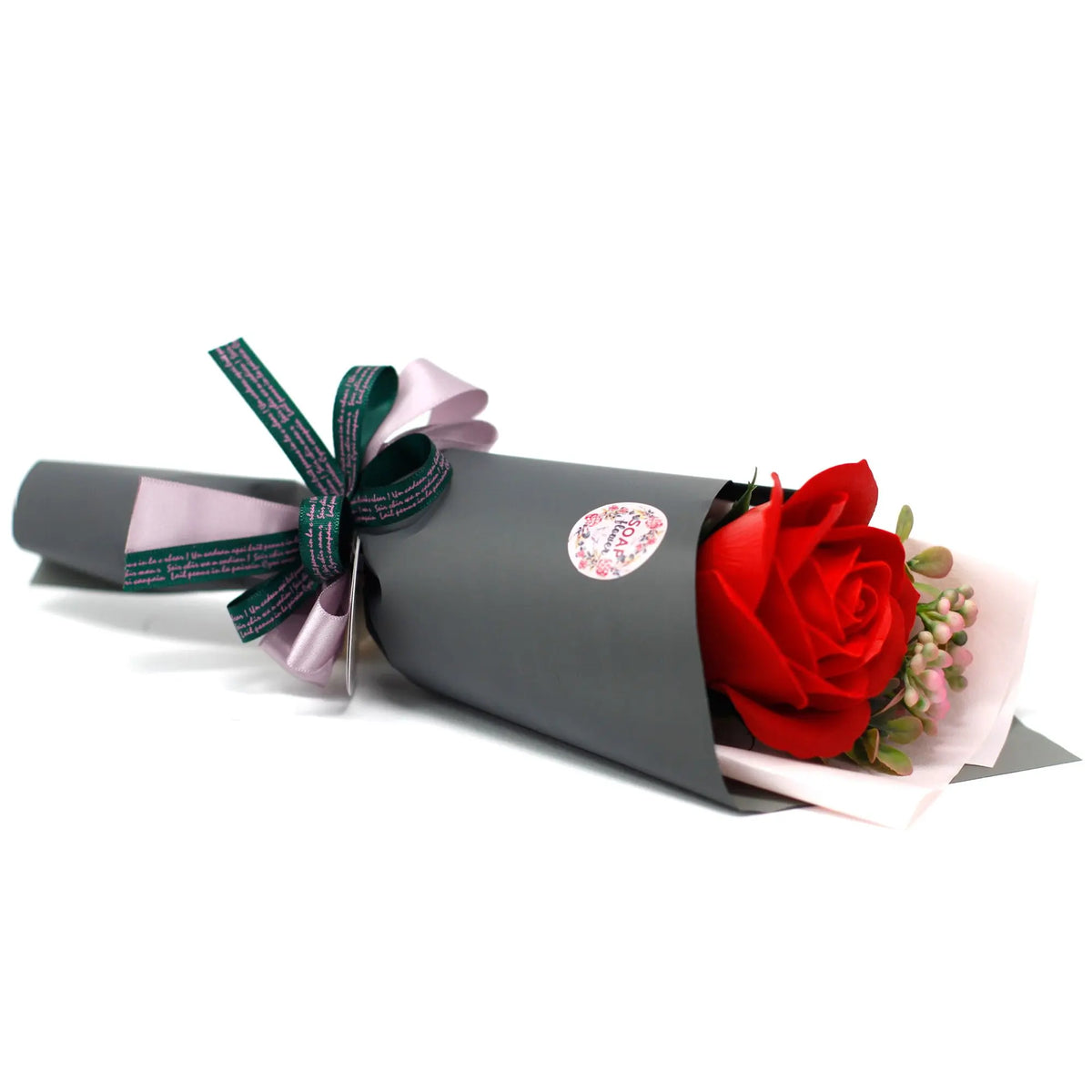 Ramo de regalo con una rosa roja de jabón, envuelta en papel gris con lazos decorativos, sobre fondo blanco.