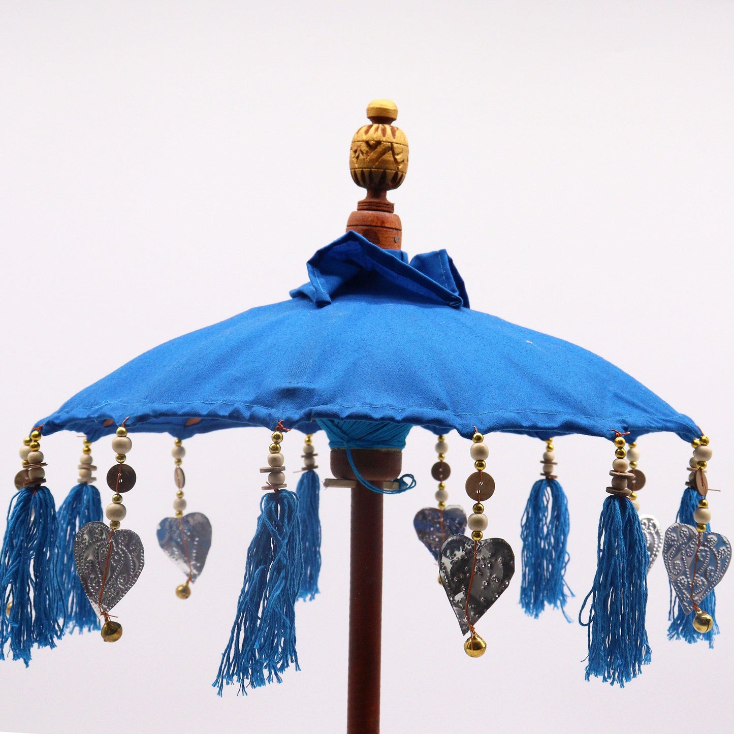 Sombrilla decorativa azul de algodón, con borlas, cuentas de madera y adornos metálicos en forma de corazón.