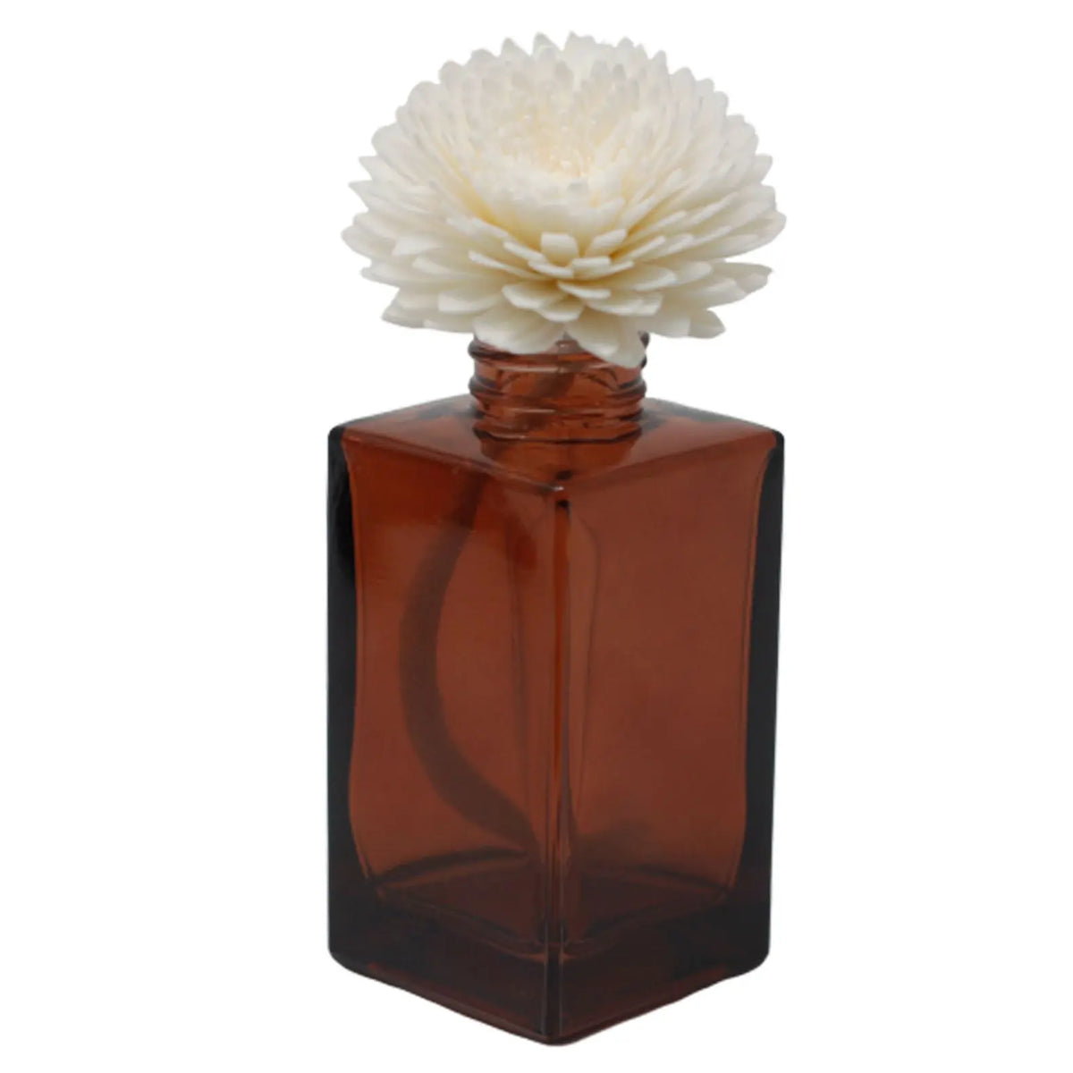 Difusor con flor blanca de madera sobre frasco de vidrio cuadrado color ámbar para aromaterapia de estilo elegante