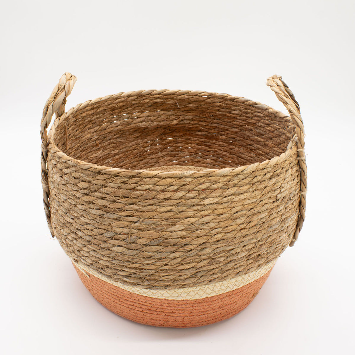 Cesta redonda de fibra natural y pasto marino con base de color naranja y dos asas laterales sobre fondo blanco.