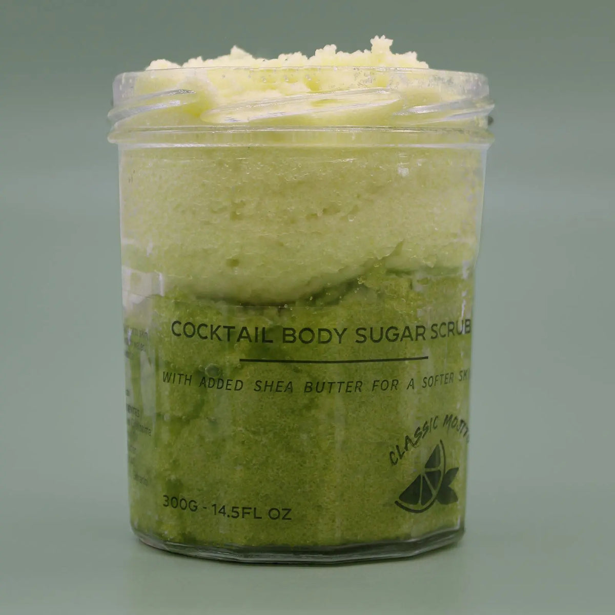 Frasco transparente con exfoliante de azúcar verde degradado, aroma Mojito, sobre fondo verde claro. 300g.