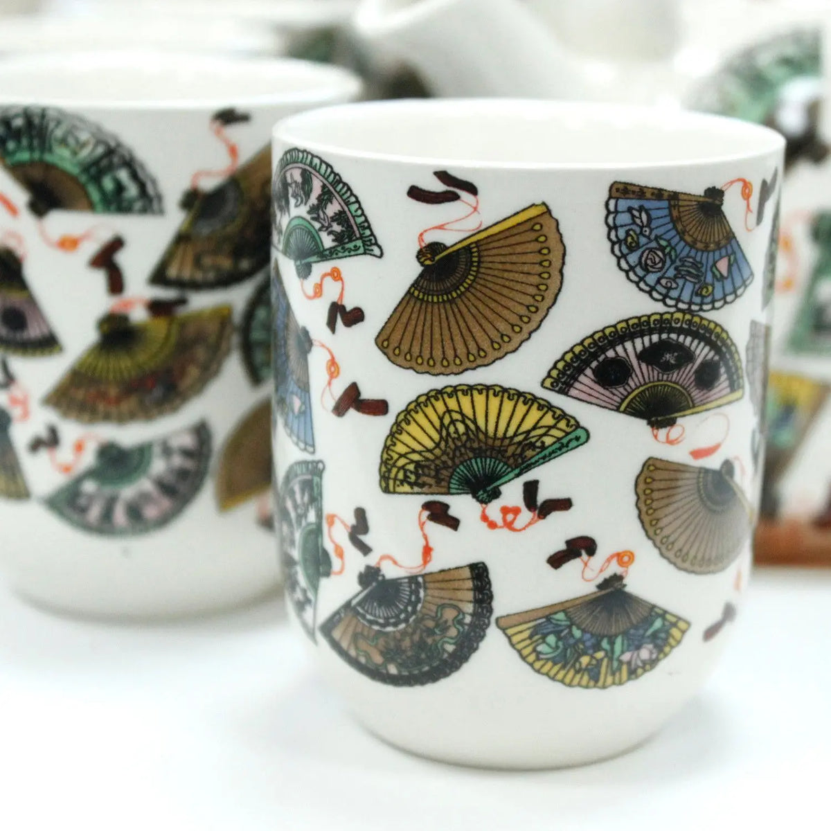 Tazas de cerámica blanca con diseño estampado de abanicos chinos coloridos, forma cilíndrica y acabado brillante.