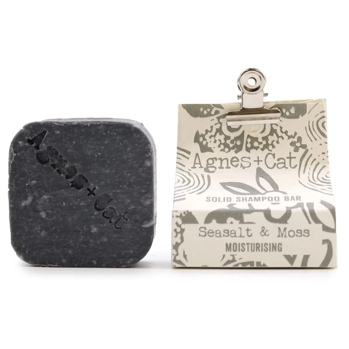 Champú sólido gris de sal marina y musgo Agnes + Cat junto a su envoltorio de papel estampado con clip metálico.