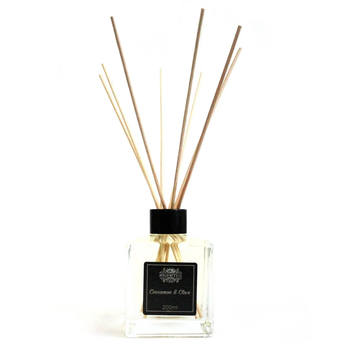 Difusor de varillas con frasco de cristal cuadrado, tapa negra y etiqueta de canela y clavo sobre fondo blanco.