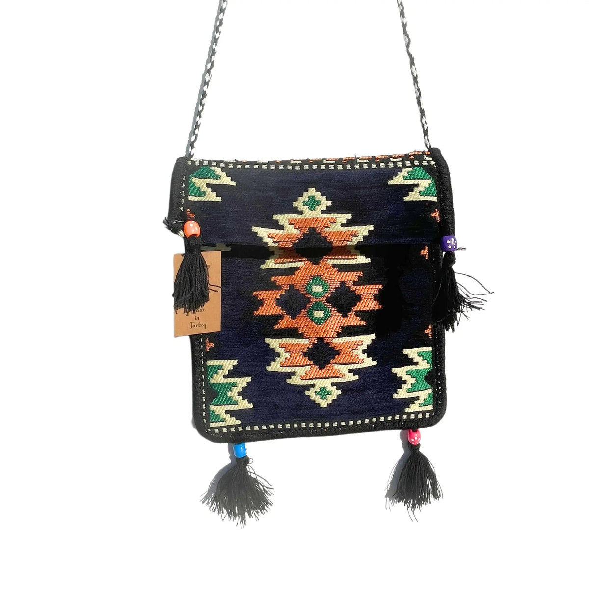 Bolso bandolera de kilim azul marino con diseño geométrico, borlas negras decorativas y correa trenzada estilo festival