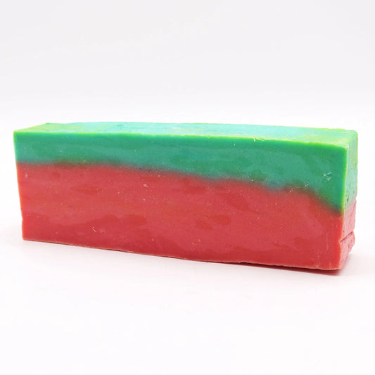 Barra rectangular de jabón artesanal bicolor: franja superior verde y franja inferior roja, sobre fondo blanco.