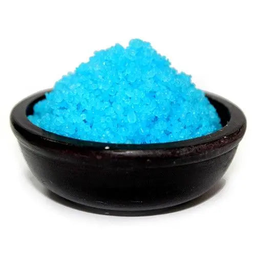 Cuenco negro pequeño lleno de gránulos aromáticos de color azul brillante sobre un fondo blanco.