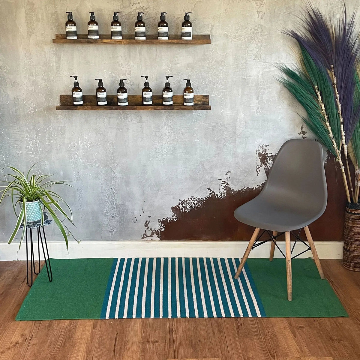 Alfombra de algodón rectangular con rayas azules y verdes sobre suelo de madera en ambiente decorativo moderno y natural