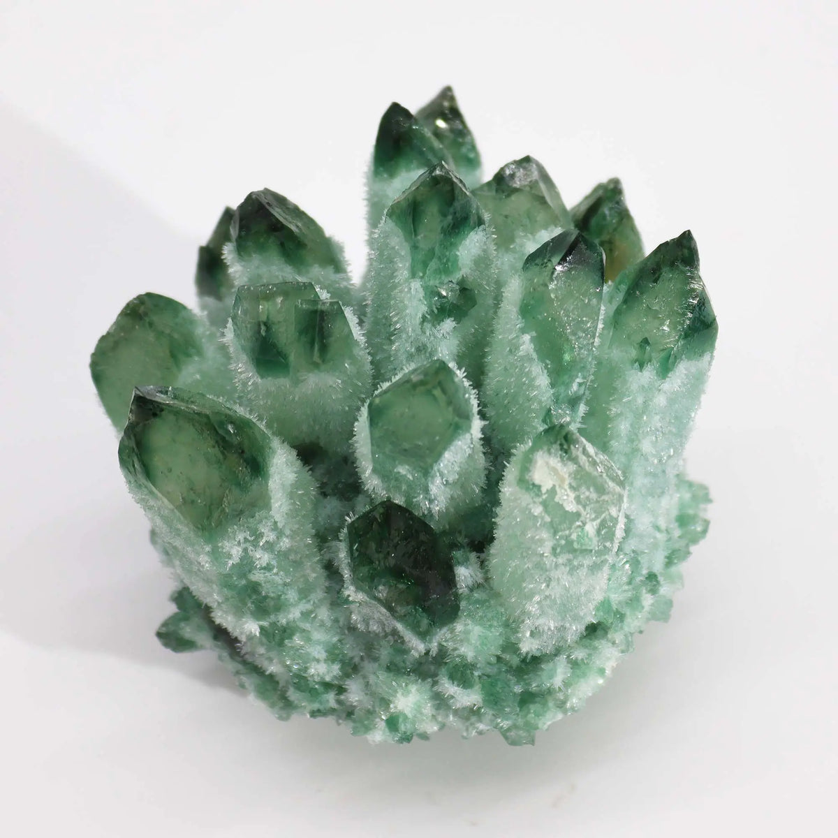 Racimo de cuarzo fantasma verde con puntas de cristal translúcidas y base texturizada sobre fondo blanco
