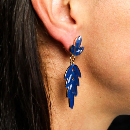 Pendientes largos colgantes con cristales azul royal en forma de hoja, montados sobre una base dorada.