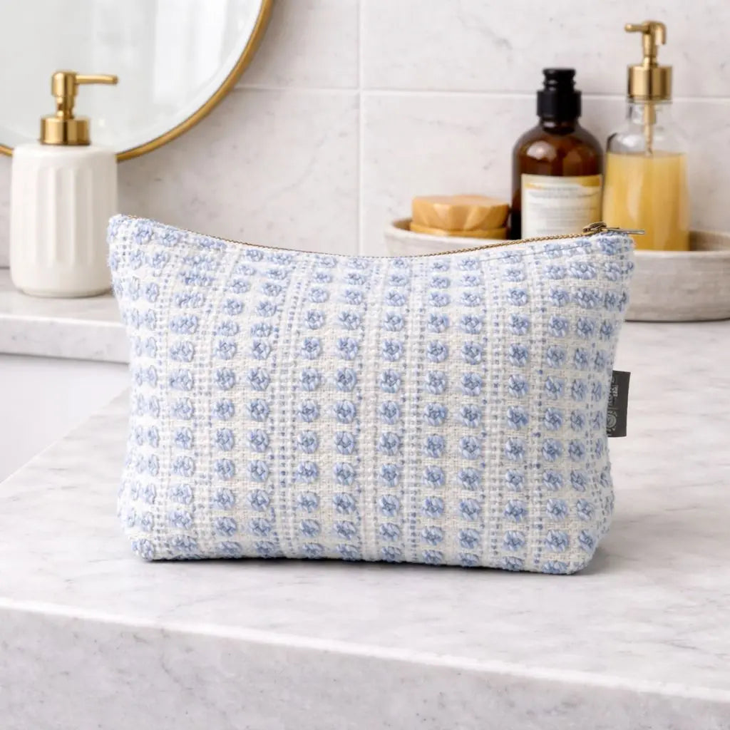 Neceser azul claro y blanco de tejido con patrón, ideal para maquillaje o artículos de tocador.