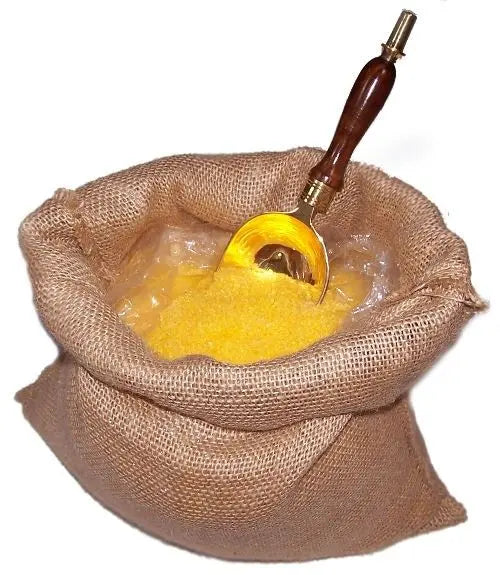 Saco de yute con sales de baño amarillas estimulantes Ancient Wisdom y una cuchara metálica con mango de madera.