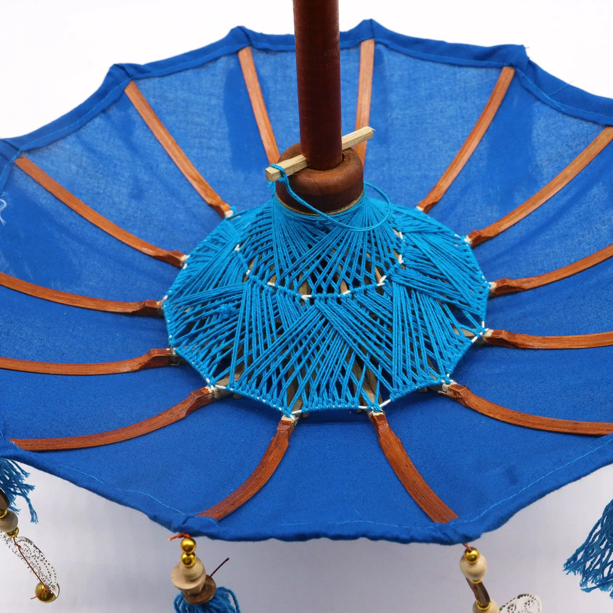 Sombrilla decorativa turquesa de algodón y bambú, con tejido manual central y detalles colgantes, estilo artesanal.