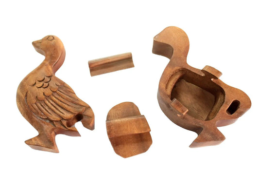 Caja mágica de madera tallada con forma de pato, desmontada en tres piezas sobre fondo blanco. Estilo artesanal.