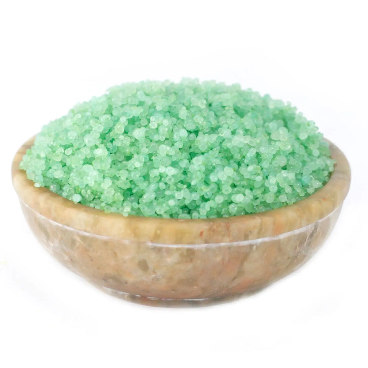 Cuenco de piedra natural lleno de gránulos aromáticos pequeños de color verde brillante sobre fondo blanco.