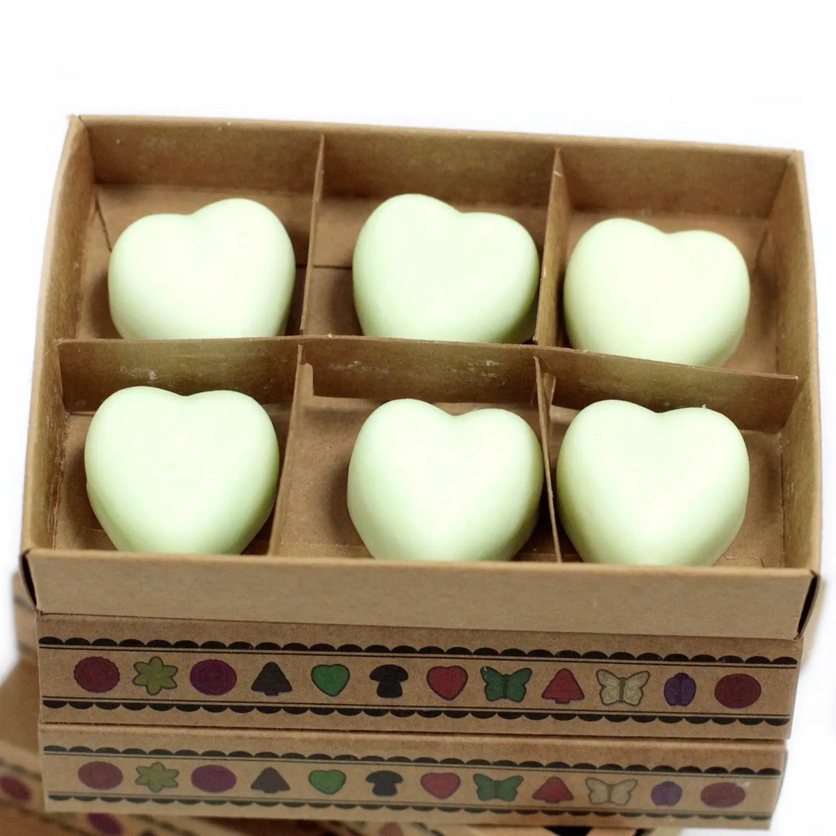 Seis ceras de soja en forma de corazón color verde menta, dentro de una caja de regalo de cartón kraft con adornos.