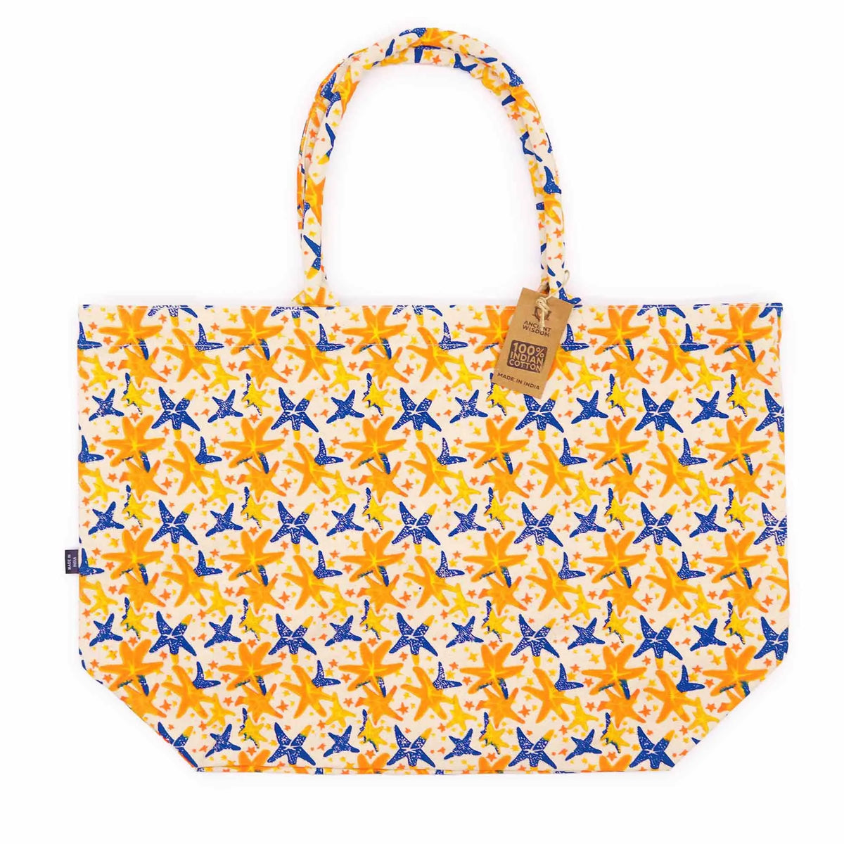 Bolsa tote de algodón con estampado de estrellas de mar azules y amarillas sobre fondo crema y asas trenzadas.