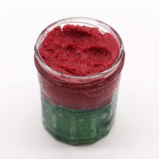 Frasco de vidrio con exfoliante corporal de azúcar rojo brillante y textura granular sobre fondo blanco.