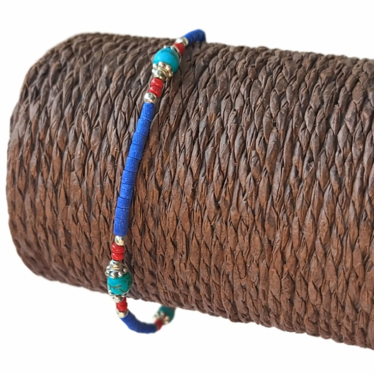 Pulsera de cuentas de cerámica azul, roja y verde con detalles metálicos; estilo bohemio y vibrante.