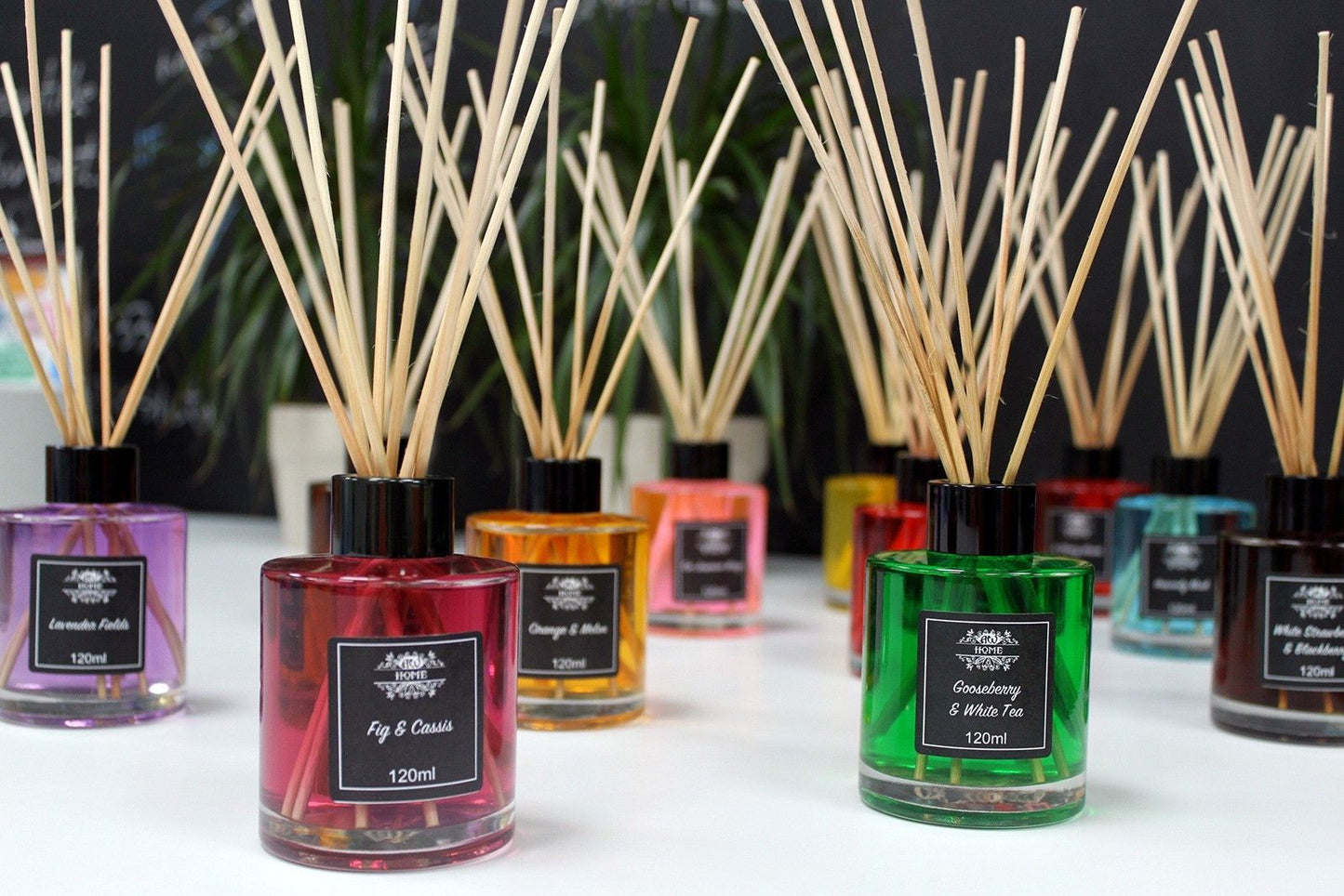 Difusores aromáticos de 120ml en frascos de vidrio de colores con varillas de madera sobre superficie blanca.