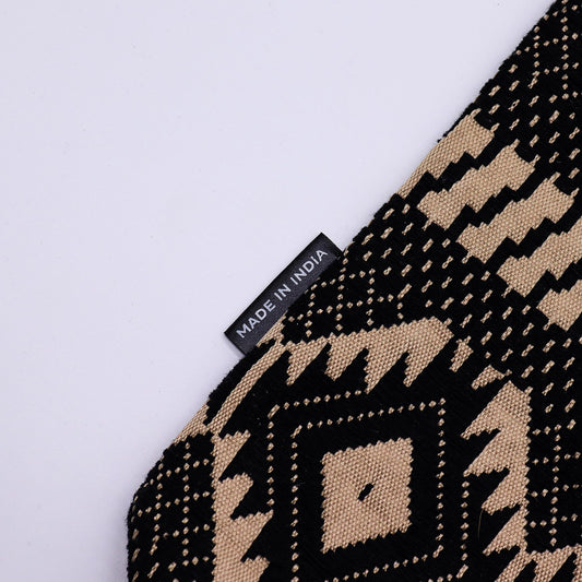 Alfombrilla decorativa de algodón en tonos negro y beige con diseño geométrico, hecha en India.
