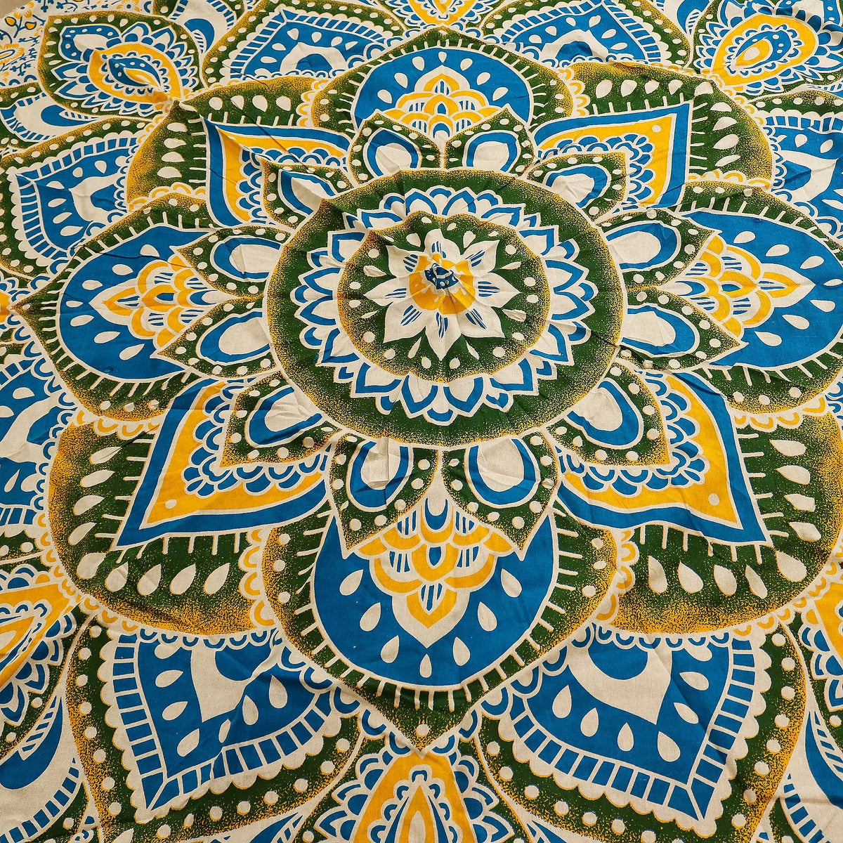 Tapiz redondo de algodón con diseño de mandala en tonos amarillo, azul y verde. Patrón floral y geométrico complejo.