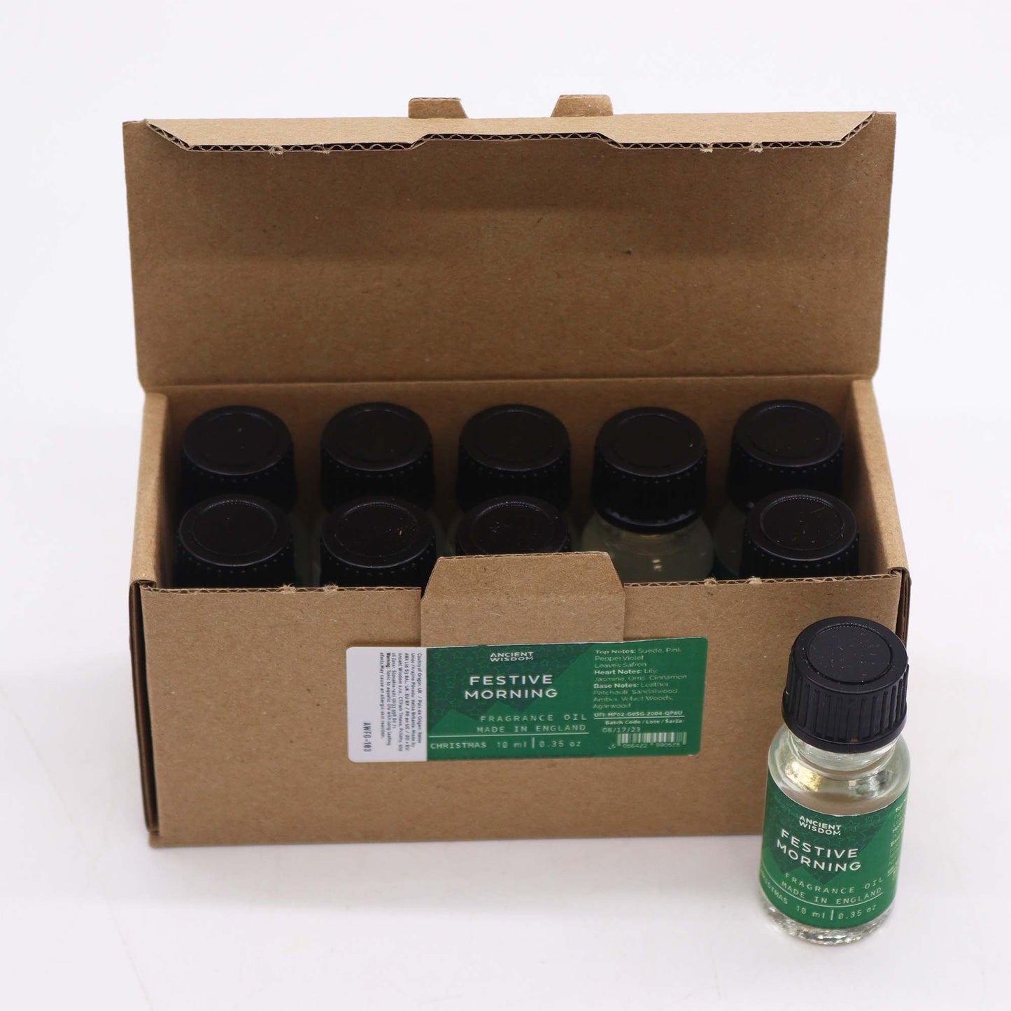 Caja de cartón con 10 frascos de aceite de 10ml, tapa negra y etiqueta verde con nombre "Festive Morning". Fondo blanco.