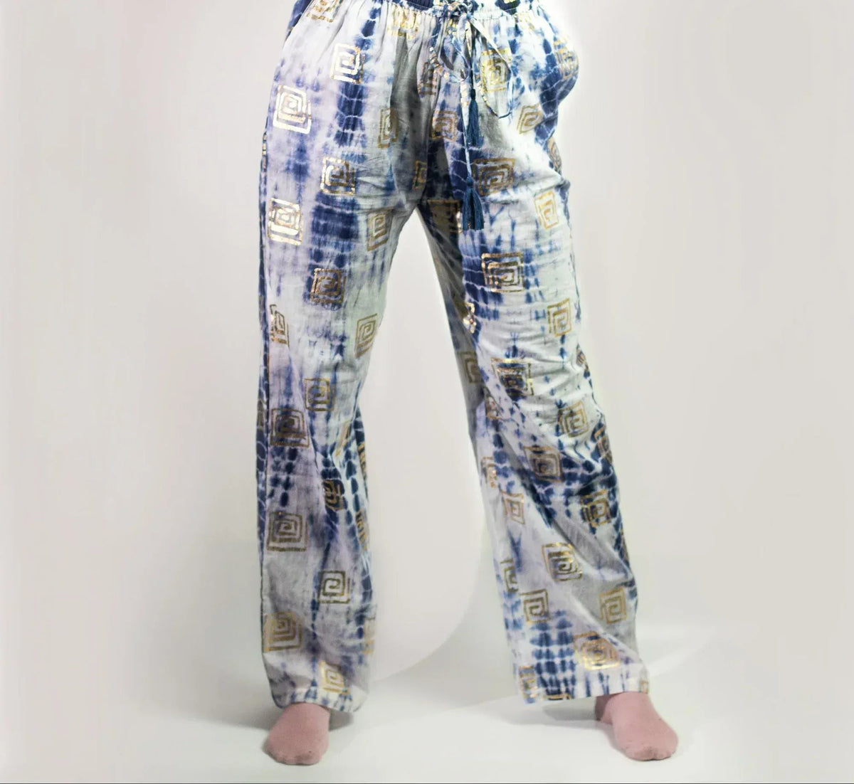 Pantalones lounge de tela fluida con estampado tie-dye azul y blanco y detalles de motivos griegos en dorado.