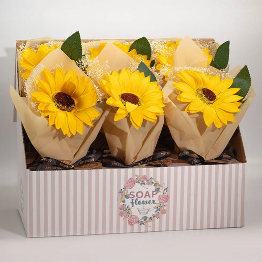 Expositor con ramos de girasoles de jabón amarillos, envueltos en papel craft con detalles de flores blancas y cinta.