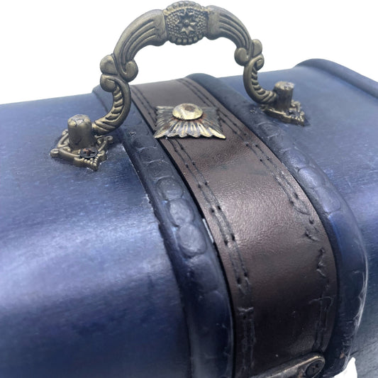 Cofre vintage azul verdoso con correa de cuero sintético, textura de piel de reptil y asa decorativa de metal dorado.
