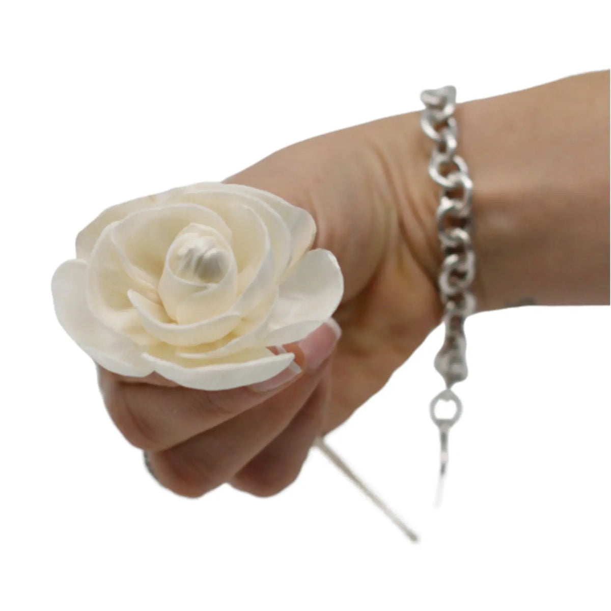 Mano sosteniendo una rosa blanca difusora hecha de madera clara con una caña fina, estilo artesanal y natural.