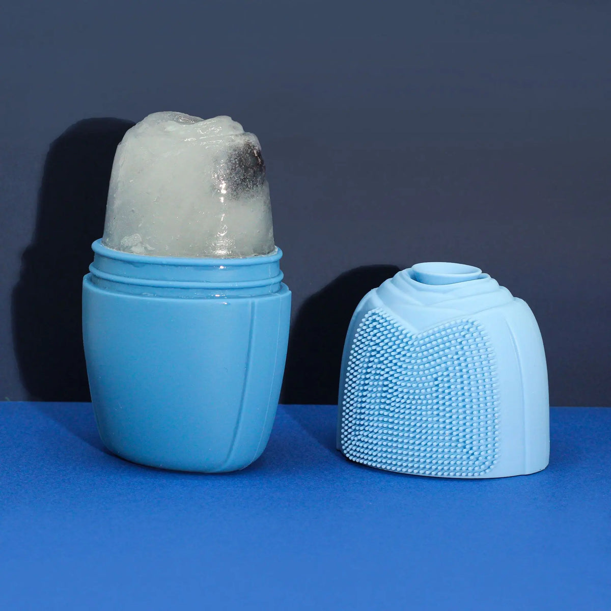 Rodillo de hielo de silicona azul con bloque de hielo, incluye tapa con cerdas exfoliantes sobre fondo azul