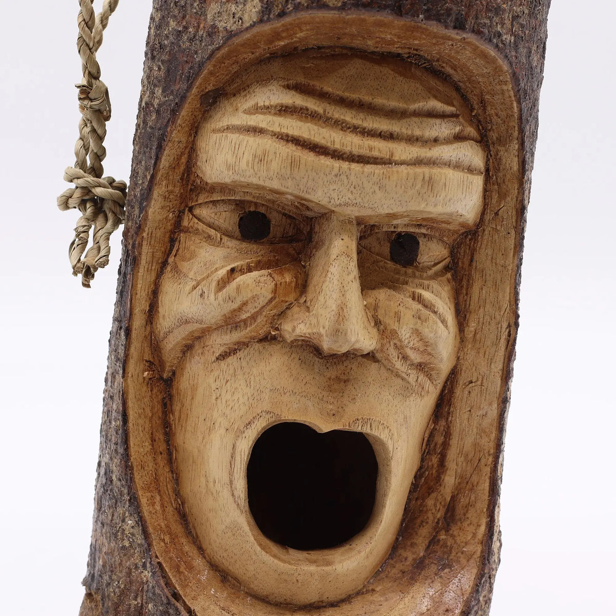 Máscara tallada en madera natural, de color marrón claro, estilo rústico y expresión facial sorprendente.