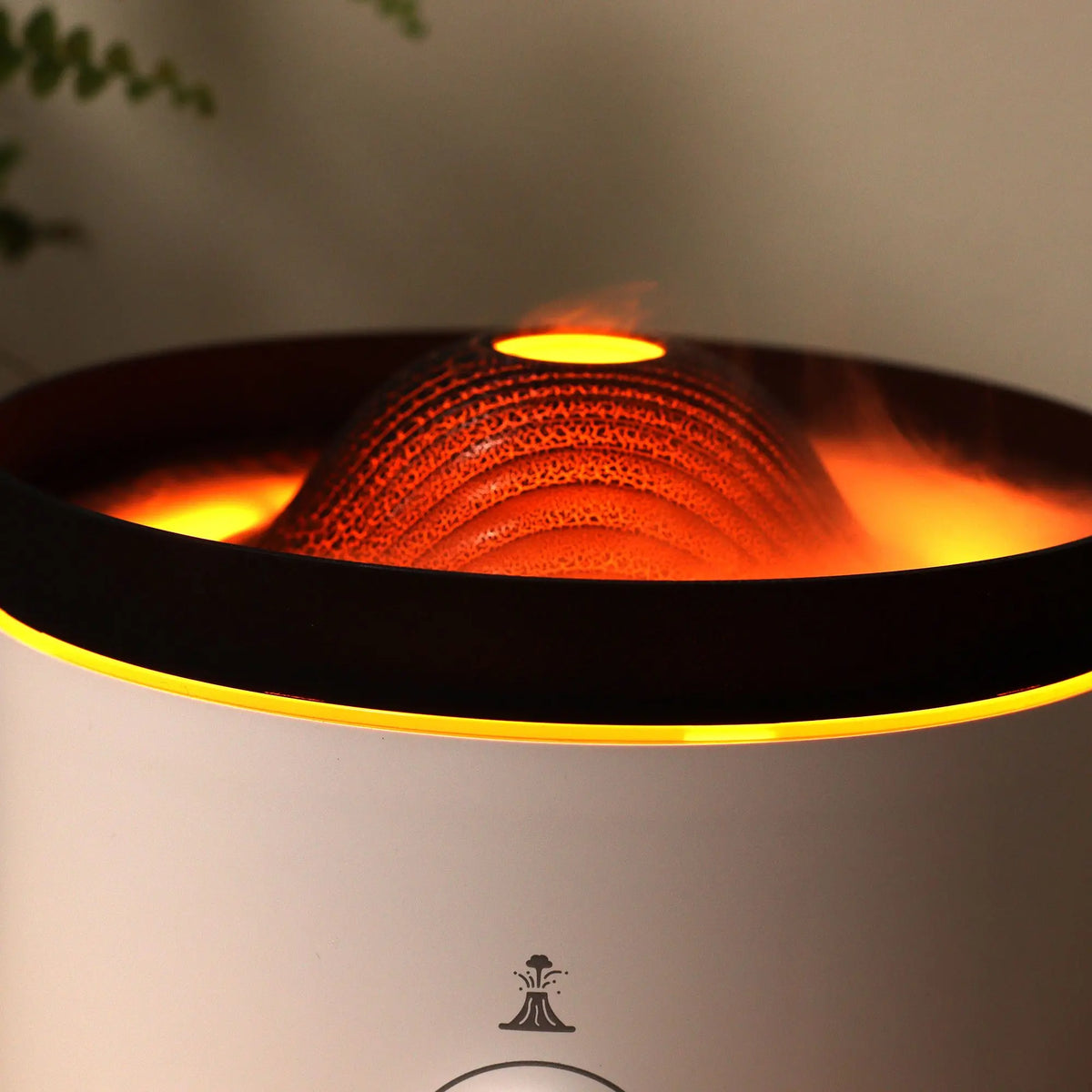 Difusor Ancient Wisdom con cúpula estilo volcán, luz cálida efecto lava y vapor ascendente sobre base blanca elegante.