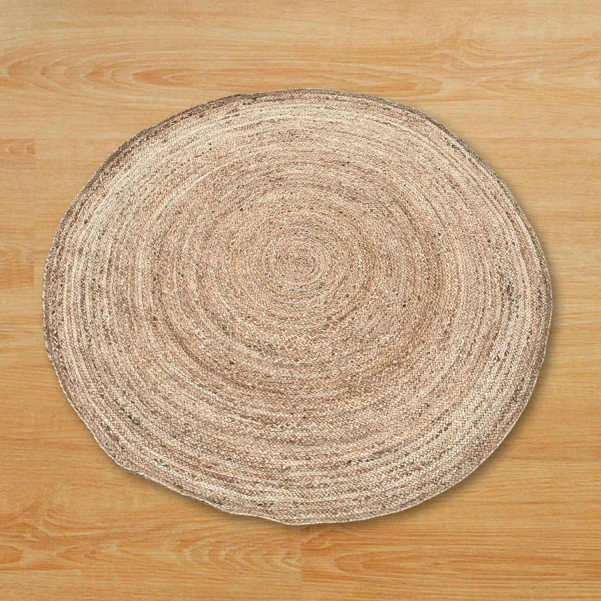 Alfombra redonda artesanal de yute y algodón reciclado en tonos naturales sobre suelo de madera.