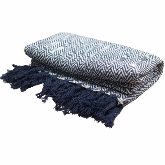 Manta de algodón estilo boho, azul marino con patrón zigzag y flecos decorativos en los extremos. Fondo blanco.