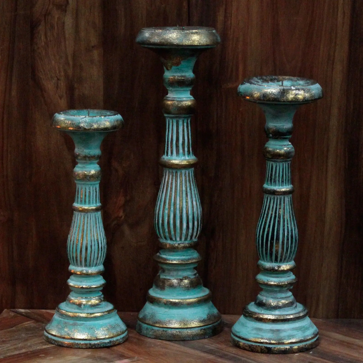 Tres candelabros vintage de madera en color turquesa con detalles dorados, acabado desgastado y diseño torneado.