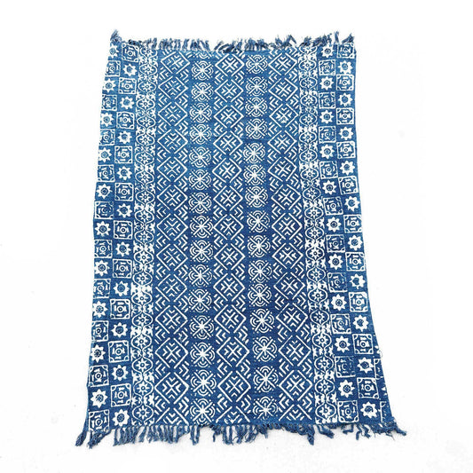 Manta azul con estampado blanco geométrico y flecos, ideal para decoración y comodidad.