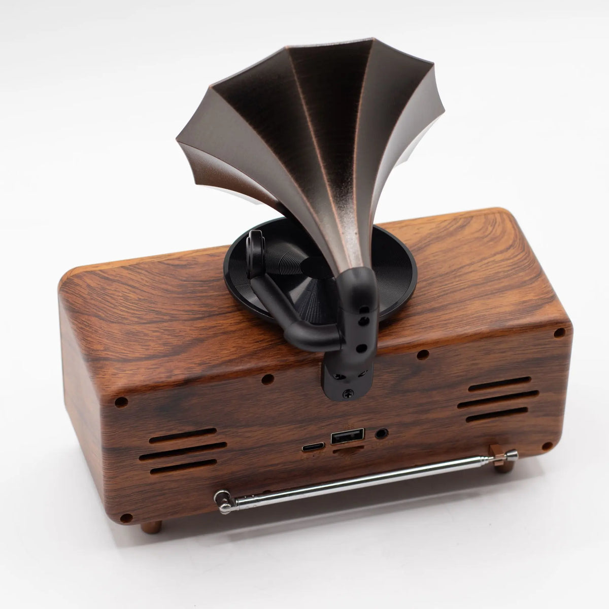 Altavoz Bluetooth retro tipo gramófono, con base de madera veteada, bocina de metal oscuro y antena plegable.