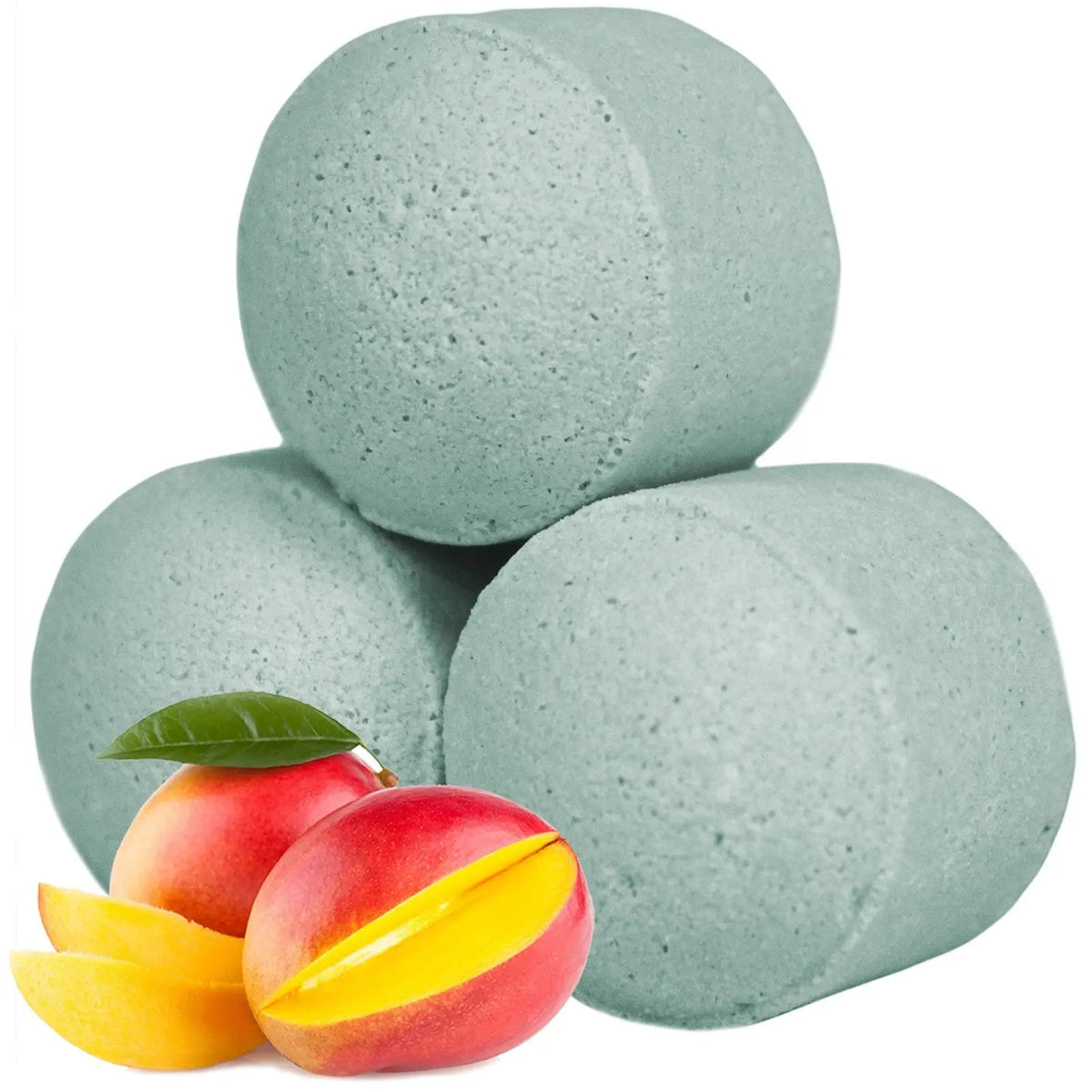 Mini bombas de baño cilíndricas de color verde claro junto a mangos frescos sobre fondo blanco.