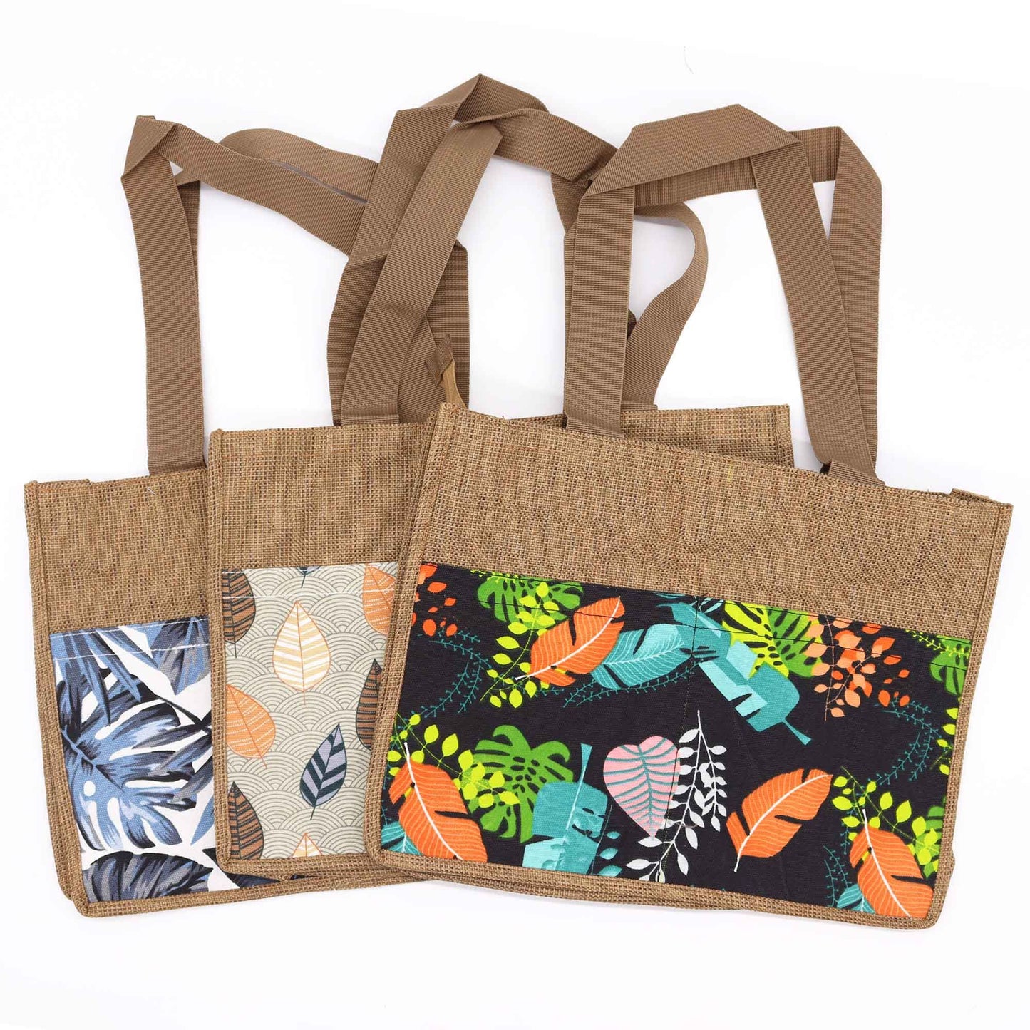Tres bolsas de yute con asas marrones, rectangulares, con bolsillos frontales estampados con coloridos motivos de hojas.