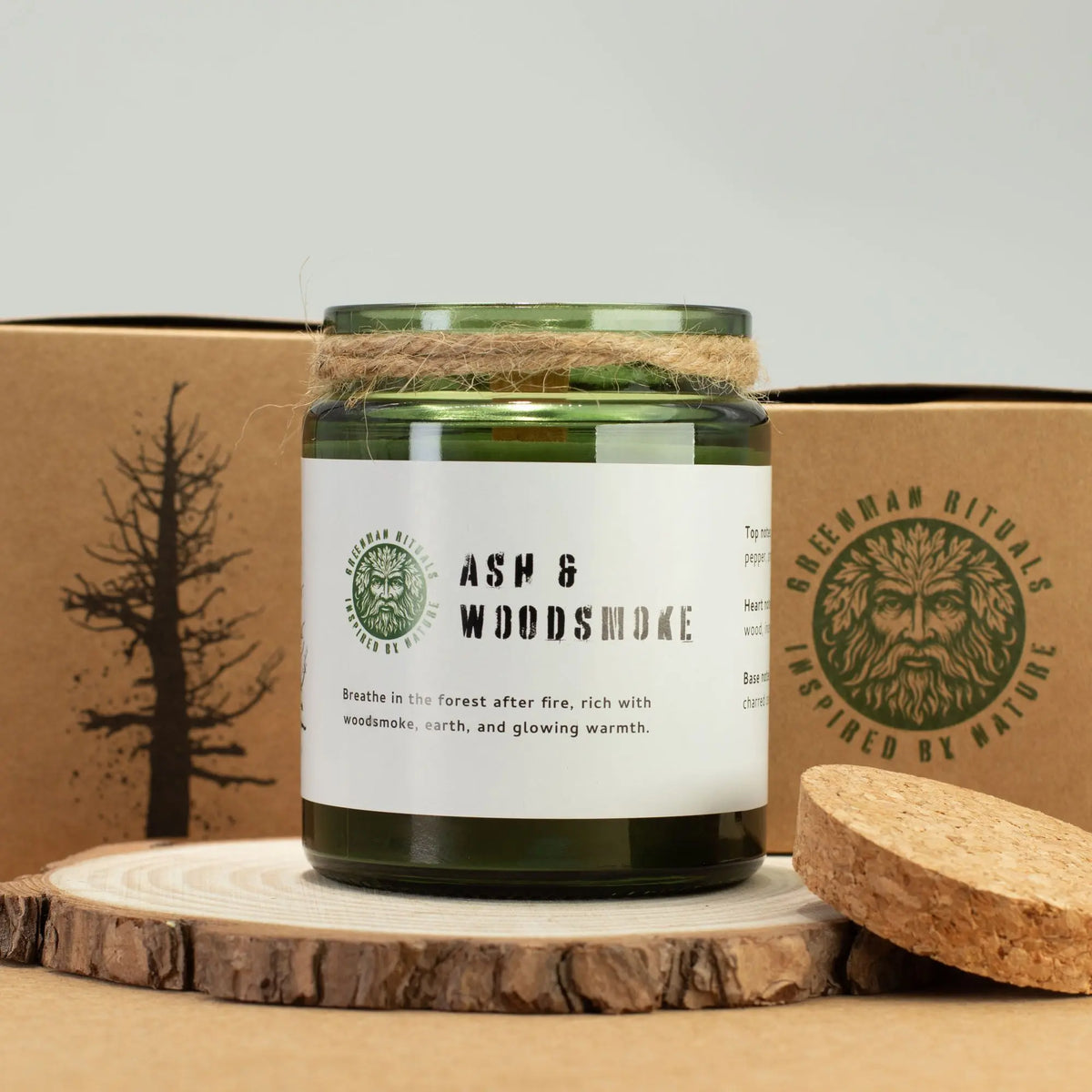 Vela verde "Ash & Woodsmoke" en tarro de vidrio, con cuerda natural, aroma a leña y tierra, estilo rústico.