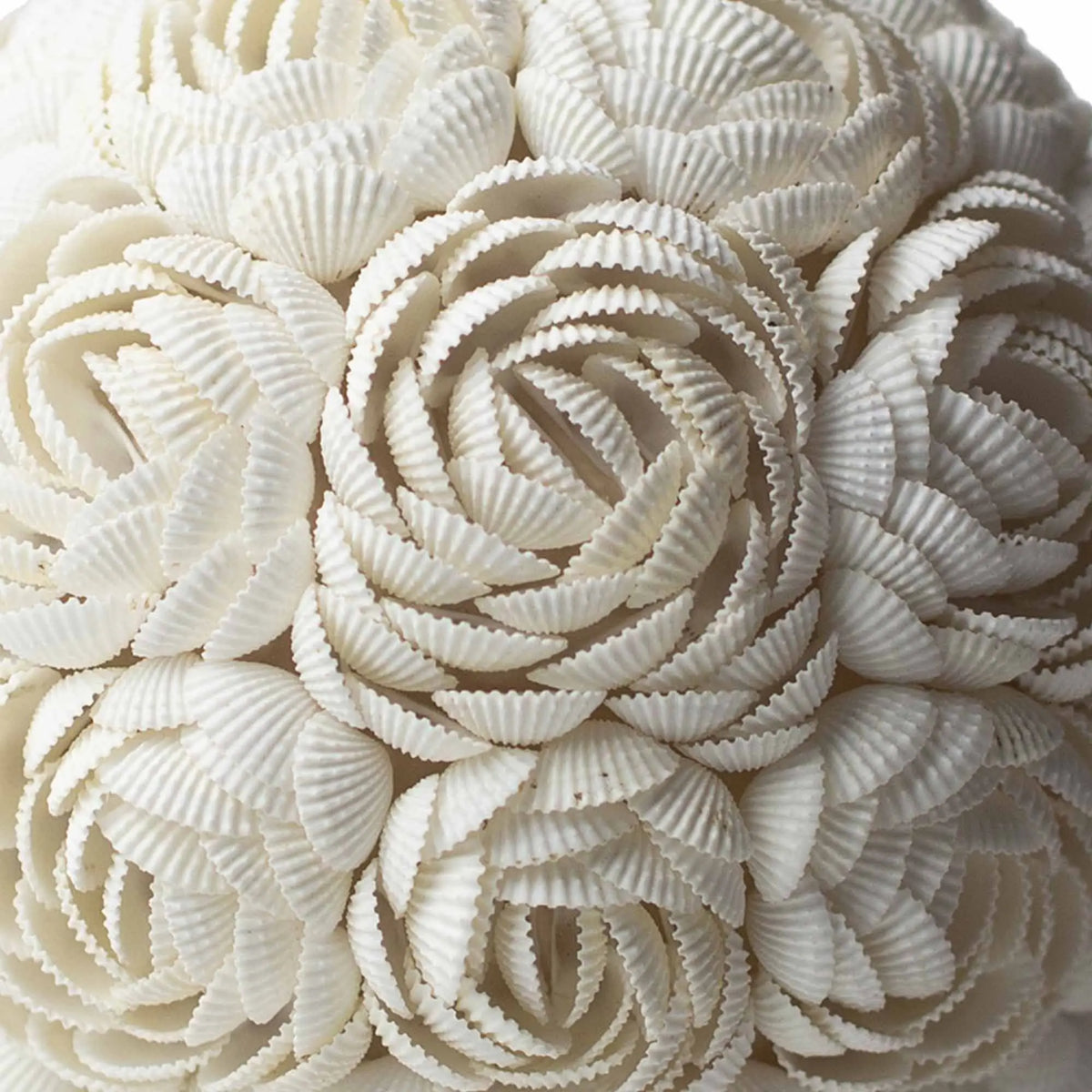 Lámpara estilo boho hecha a mano con conchas blancas dispuestas en forma de flores, creando una textura superpuesta.