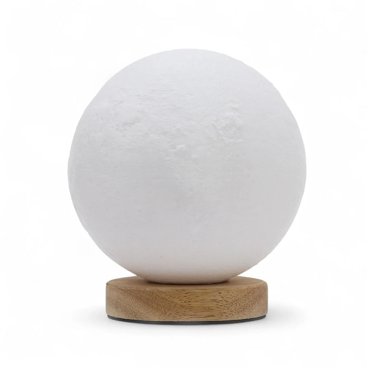 Lámpara esférica blanca con textura de luna sobre base circular de madera clara sobre fondo blanco.