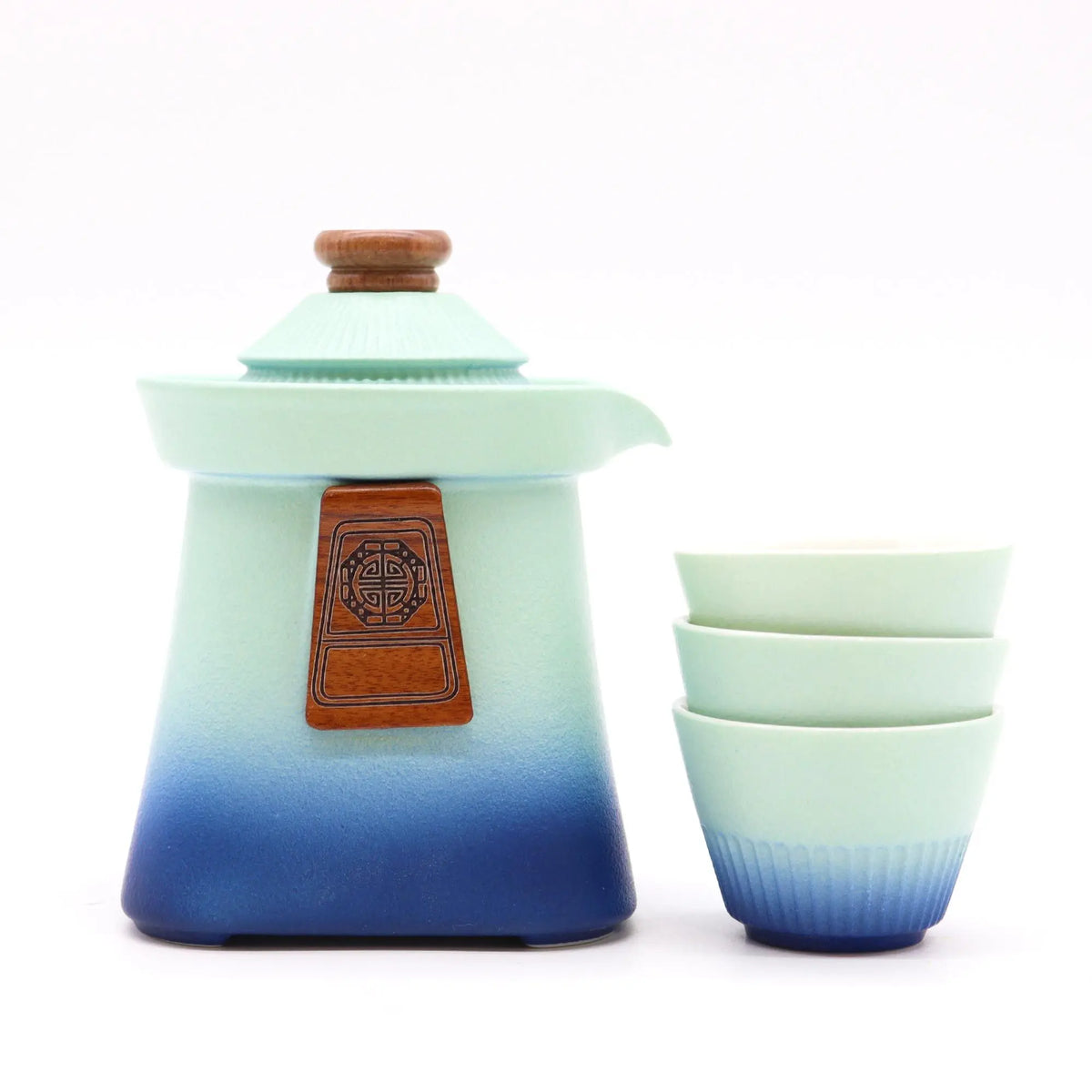 Juego de té en cerámica azul degradado con tetera y tres tazas, detalles en madera y diseño oriental sobre fondo blanco