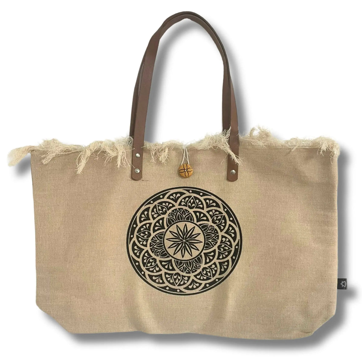 Bolso de tela natural con bordes deshilachados, estampado de mandala negro y asas largas de cuero marrón.